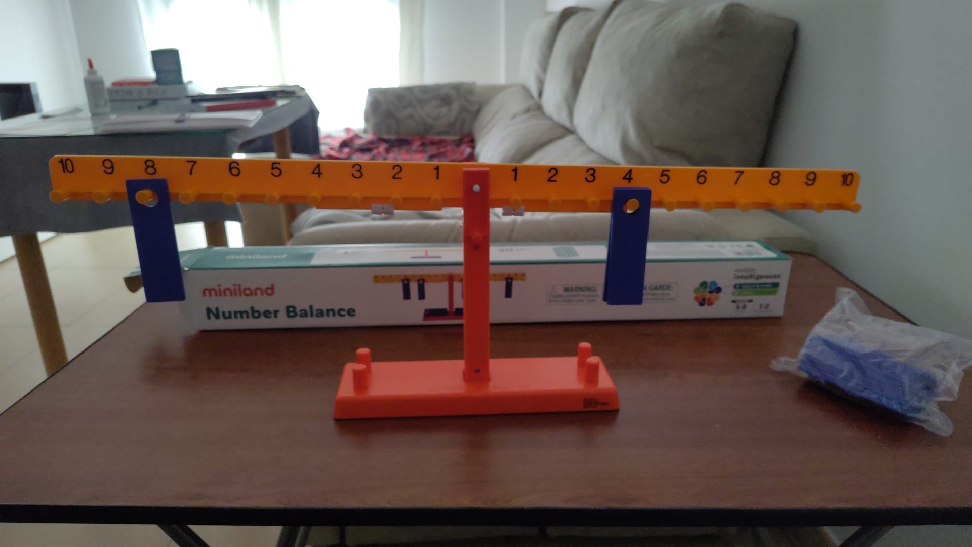 Una balanza con los dos brazos numerados, del 1 al 10, alejándose del punto de apoyo. Pesas colgadas en distintos puntos.