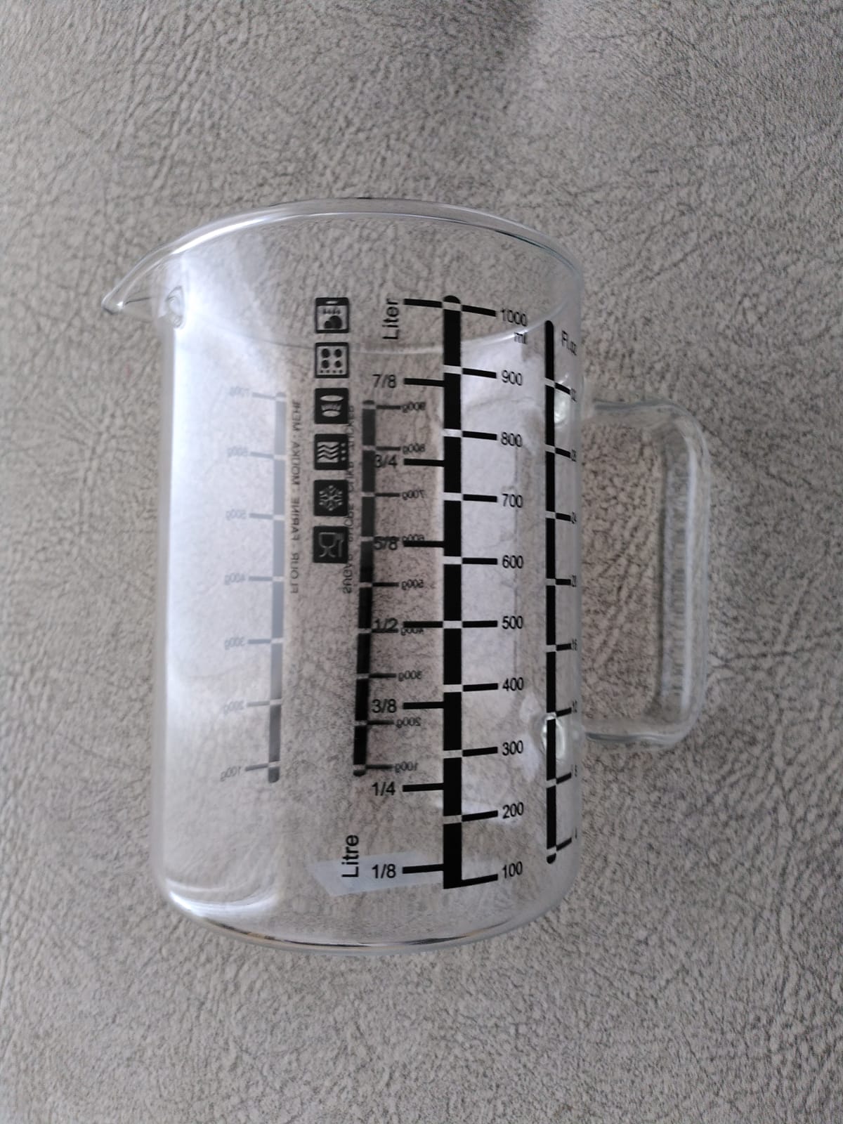 Jarra medidora de 1 L, con varias escalas, de vidrio borosilicato. Parece un vaso de precipitados con asa.